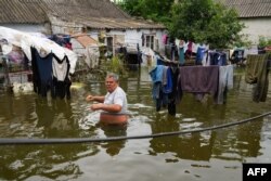 A local resident walks in flooded yard of his house in Afanasiyivka, Mykolayiv region on June 10, 2023, following damages sustained at Kakhovka hydroelectric power plant dam.