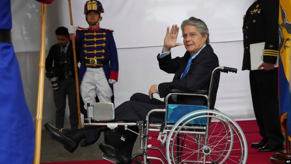 ARCHIVO: El presidente de Ecuador, Guillermo Lasso, en silla de ruedas, saluda a la prensa en el palacio de gobierno el lunes 6 de marzo de 2023. 