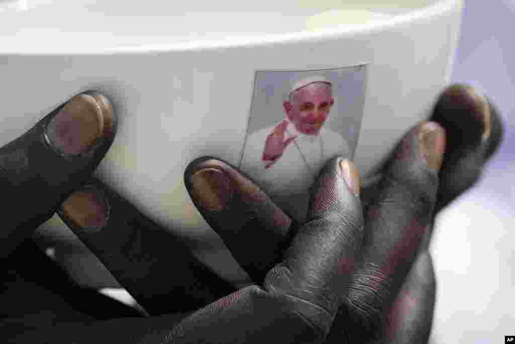 A priest holds a sacrament bowl showing a photograph of Pope Francis at a Holy Mass at the John Garang Mausoleum in Juba, South Sudan Sunday, February 5, 2023.&nbsp;