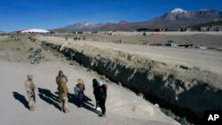 Soldados chilenos hablan con migrantes antes de llevarlos a un refugio donde la policía los registra, cerca de Colchane, Chile, el 1 de marzo de 2023. 