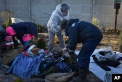 Warga setempat berusaha mengumpulkan barang-barang mereka dari gedung yang hancur akibat serangan Rusia di distrik Zaporizhzhia, Ukraina, Jumat 31 Maret 2023.