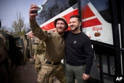 In this photo provided by the Ukrainian Presidential Press Office, Ukrainian president Volodymyr Zelenskyy poses for a selfie with a soldier at a position in Avdiivka, Donetsk region, Ukraine, April 18, 2023.