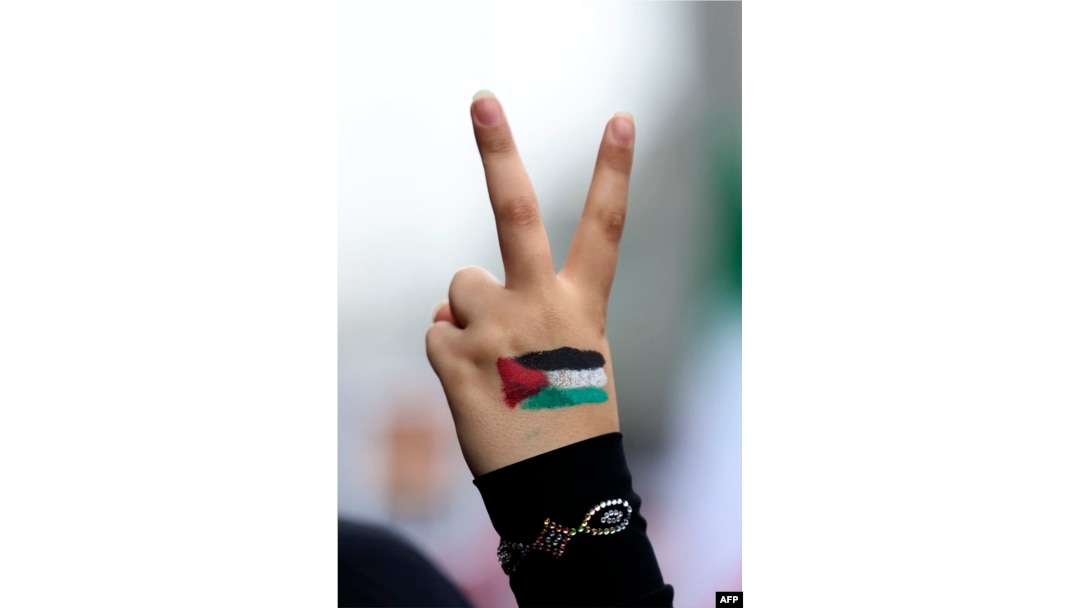 Seorang perempuan mengacungkan tangan bergambar bendera Palestina dan jarinya membentuk tanda kemenangan dalam unjuk rasa di luar bekas gedung Kedutaan Besar AS di Teheran , Iran, Sabtu, 4 November 2023. (Foto: Atta Kenare/AFP)