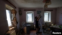 Resident Natalia removes debris in a house damaged by recent shelling in the course of Russia-Ukraine conflict in the Donetsk region, Russian-controlled Ukraine, July 6, 2024.