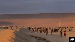 FILE - Migrants walk through the desert on the border between Chile and Peru, near Arica, Chile, May 2, 2023.