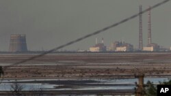 জাপোরিঝিয়া পারমাণবিক বিদ্যুৎ কেন্দ্রটি রাশিয়া-অধিকৃত ইউক্রেনের এনারগোদারে বাঁধ ধ্বসের পরে কাখোভকা জলাধারের পিছনে দেখা যাচ্ছে। ( ২৭ জুন, ২০২৩)