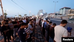 Warga Palestina melakukan salat berjemaah di sepanjang jalan pesisir di Kota Gaza 29 Mei 2023. REUTERS/Mohammed Salem