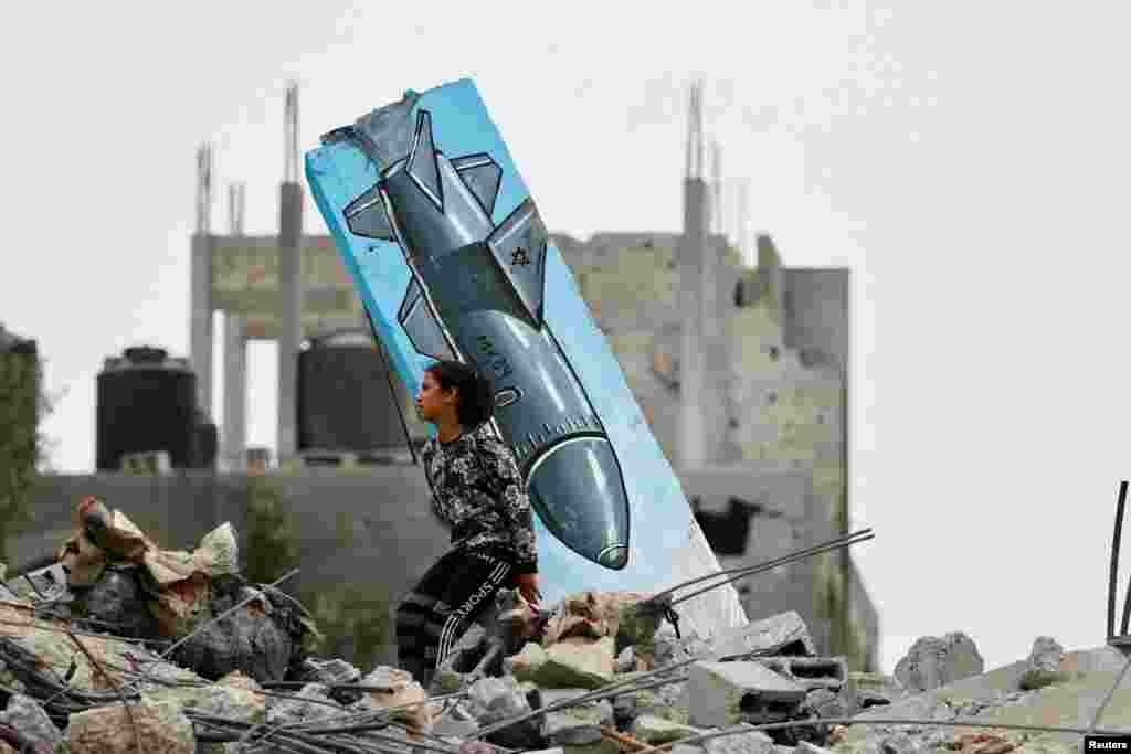 A Palestinian girl sits on the remains of a destroyed house, next to a graffiti of a missile drawn by Hussein Abu Sadeq, on houses destroyed by Israel in recent Israeli-Gaza fighting, in Deir Al-Balah, central Gaza Strip.