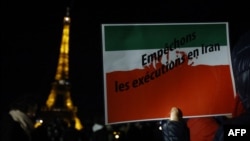 FILE - A protester holds a slogan reading in French " Stop the executions in Iran" during a gathering in a show of support to the Iranian people, in Paris, Jan. 16, 2023.