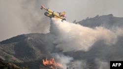 FILE - A fire fighting aircraft drops water over a wildfire close to village of Vati in the southern part of the Greek island of Rhodes, about 70 km southwest of the capital city on July 25, 2023. 