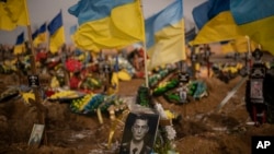 A photograph of a Ukrainian serviceman is on his grave in the Alley of Glory section of the cemetery in Kharkiv, Ukraine, Feb. 24, 2023. 