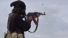 FILE - This frame grab from video posted online March 18, 2019, by the Aamaq News Agency, then a media arm of the Islamic State group, shows an IS fighter firing his weapon during clashes with U.S.-backed Syrian Democratic Forces in Baghouz, Syria.