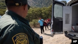 FILE - A Border Patrol agent waits on migrants, June 5, 2024, near Dulzura, Calif. President Joe Biden on June 4 halted asylum processing for many migrants, but he's set to announce deportation protection and work permits for spouses of U.S. citizens.
