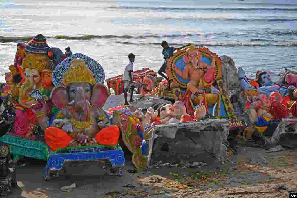 Boys stand next to the remains of idols of the Hindu deity Ganesha after they were immersed by devotees in the Bay of Bengal during the Ganesh Chaturthi festival in Chennai, India.