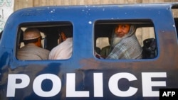 FILE - Detained Afghan refugees sit in a police van during a search operation to identify alleged illegal immigrants, on the outskirts of Karachi, Pakistan, Nov. 17, 2023.