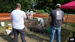 Omaha Tribe members Mark Parker, left, and Jarell Grant, both of Macy, Nebraska, watch as workers dig for the suspected remains of children who once attended the Genoa Indian Industrial School, in Genoa, Nebraska, July 11, 2023.
