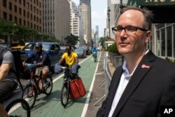Robert Slone, chief scientist and senior vice president of UL Solutions, stands by a bike lane as riders on e-bikes pass by on 2nd Avenue in Manhattan in New York, on Monday, July 17, 2023.