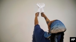 Crystal Kornickey holds up casts of her hands in a studio at the Gibbes Museum of Art in Charleston, S.C., on Thursday, Feb. 16, 2023. (AP Photo/Allen G. Breed)
