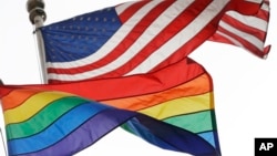 FILE - The Rainbow Flag, an international symbol of LGBT liberation and pride, flies beneath the American flag at the Stonewall National Monument on Oct. 11, 2017, in New York.