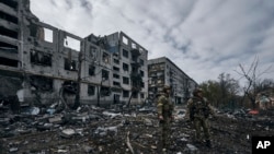 FILE - Ukrainian soldiers pass by houses ruined in the Russian shelling in Bakhmut, Donetsk region, Ukraine, Nov. 10, 2022