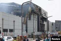 Petugas pemadam kebakaran berupaya memadamkan api di pabrik baterai yang terbakar di Hwaseong, Korea Selatan, 24 Juni 2024. (REUTERS/Kim Hong-ji)