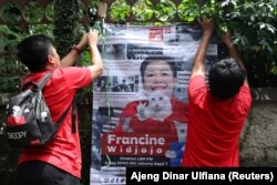 Francine Widjojo, 44, calon anggota DPRD dari PSI, memasang poster kampanyenya bersama asisten di Jakarta, 28 Januari 2024. (Foto: Ajeng Dinar Ulfiana/Reuters)