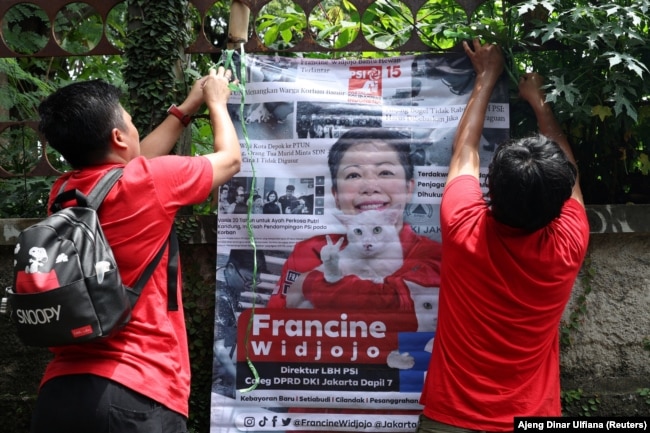 Francine Widjojo, 44, calon anggota DPRD dari PSI, memasang poster kampanyenya bersama asisten di Jakarta, 28 Januari 2024. (Foto: Ajeng Dinar Ulfiana/Reuters)