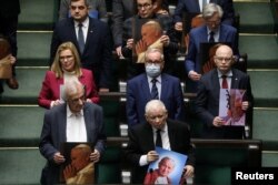Jaroslaw Kaczynski, leader of Law and Justice and lawmakers hold images of Pope John Paul II during debate about resolution on defending the name of John Paul II, at parliament, March 9, 2023. (Slawomir Kaminski/Agencja Wyborcza.pl via Reuters)