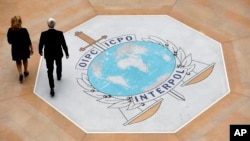 FILE - People walk on the Interpol logo at the agency headquarters in Lyon, France, Nov. 8, 2018. 'The volume of financial fraud stemming from West Africa is alarming and increasing,' says Isaac Oginni, director of Interpol's Financial Crime and Anti-Corruption Centre.