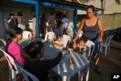 Venezuelan migrant Natalia Contreras tends to her children as they settle in to have breakfast at a shelter in Rio Branco, Brazil, June 22, 2024.