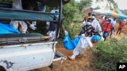 Polisi dan warga setempat mengevakuasi puluhan jenazah korban pemujaan agama ke bagian belakang truk di desa Shakahola, dekat kota pesisir Malindi, di Kenya tenggara, Minggu 23 April 2023.