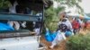 Police and local residents load the exhumed bodies of victims of a religious cult into the back of a truck in the village of Shakahola, near the coastal city of Malindi, in southeastern Kenya, April 23, 2023.