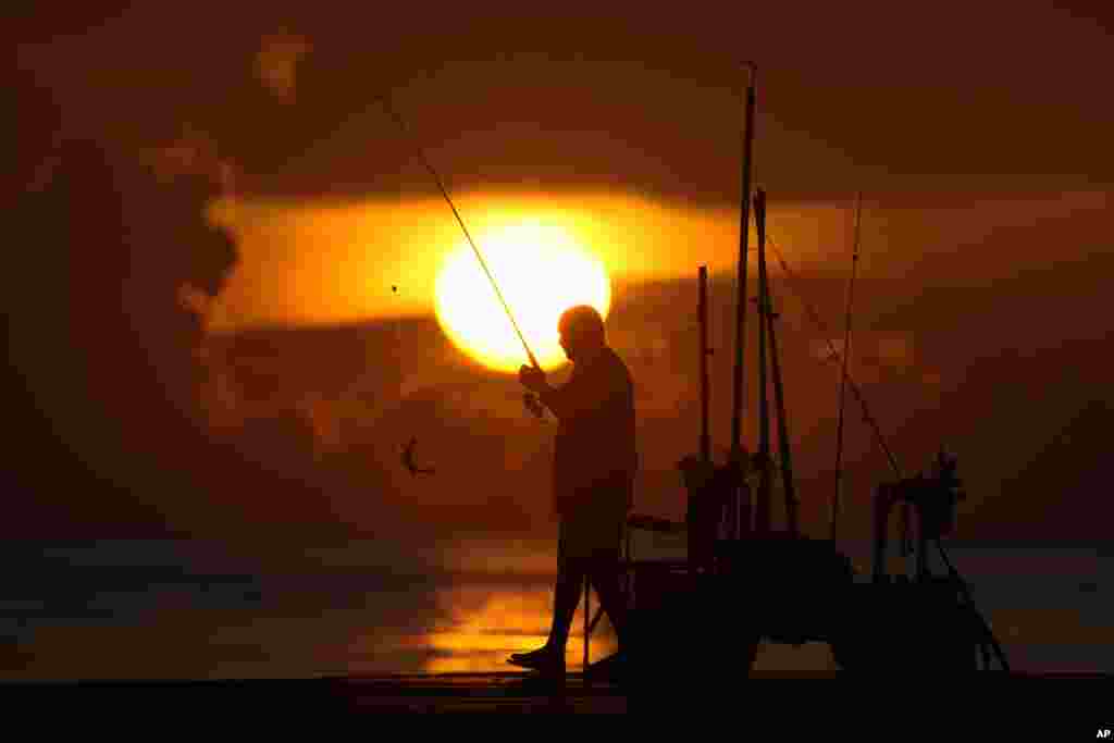 A fisherman reels in his catch as the sun rises over the Atlantic Ocean in Bal Harbour, Florida.