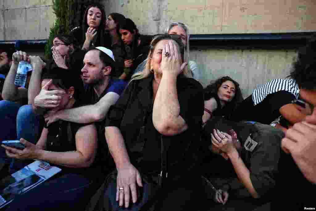 Пријателите и семејството се штитат додека се огласуваат ракетните сирени за време на погребот на Сагив Бен Зви (24), кој беше убиен по смртоносната инфилтрација на вооружени лица на Хамас од Појасот Газа, во Холон, Израел.