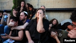 FILE - Friends and family take cover as rocket sirens sound during the funeral of Sagiv Ben Zvi, 24, who was killed following the deadly infiltration by Hamas gunmen from the Gaza Strip, in Holon, Israel, Oct. 26, 2023.