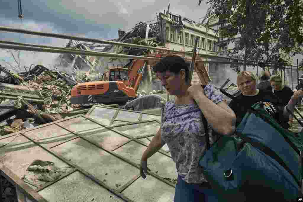 La gente carga con sus pertenencias mientras el personal del servicio de emergencia trabaja en el sitio de edificios destruidos en el centro de la ciudad patrimonial de Odesa, después de un ataque ruso el jueves 20 de julio de 2023.&nbsp;