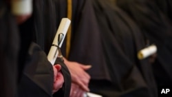 FILE - College graduates receive their diplomas in 2014.