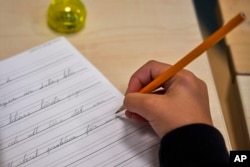 A child practices handwriting at the Djurgardsskolan elementary school in Stockholm, Sweden, Thursday, Aug. 31, 2023. (AP Photo/David Keyton)