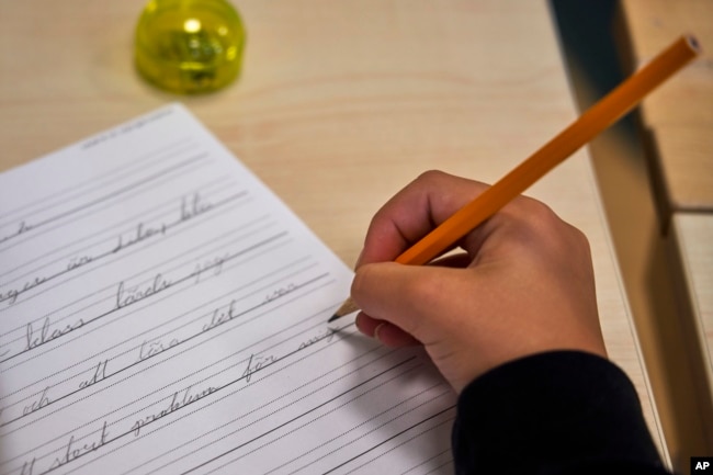 A child practices handwriting at the Djurgardsskolan elementary school in Stockholm, Sweden, Thursday, Aug. 31, 2023. (AP Photo/David Keyton)
