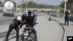 Seorang petugas polisi memeriksa pengendara motor di Haiti di Port-au-Prince, Haiti, pada 1 Juli 2023. (Foto: AP/Odelyn Joseph)