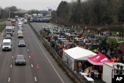 Military vehicles face farmers blocking a highway in Chilly-Mazarin, south of Paris, France, Jan. 31, 2024.