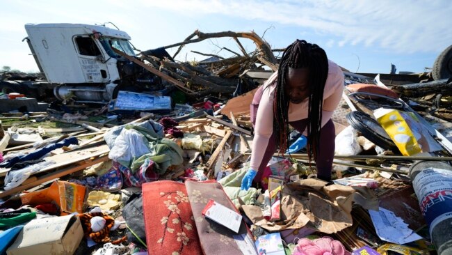 A woman sifts through belongings at the spot of a family member's home after a tornado destroyed the property two days earlier, in Rolling Fork, Mississippi, March 26, 2023.
