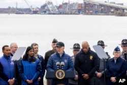 President Joe Biden, center, speaks about Maryland's collapsed Francis Scott Key Bridge, seen in the Baltimore harbor in the background, April 5, 2024.