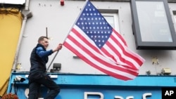 A publican puts a U.S flag up outside the Blue Square bar in Ballina, Ireland, April, 4, 2023. Excitement is building in Ballina ahead of President Biden's expected visit.