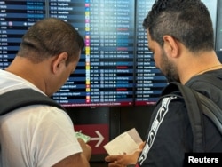 Wisatawan mengamati jadwal penerbangan setelah pemadaman siber global di bandara BER di Berlin, Jerman, 19 Juli 2024. (REUTERS/Tobias Schlie)