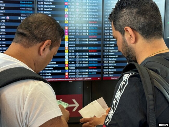 Wisatawan mengamati jadwal penerbangan setelah pemadaman siber global di bandara BER di Berlin, Jerman, 19 Juli 2024. (REUTERS/Tobias Schlie)