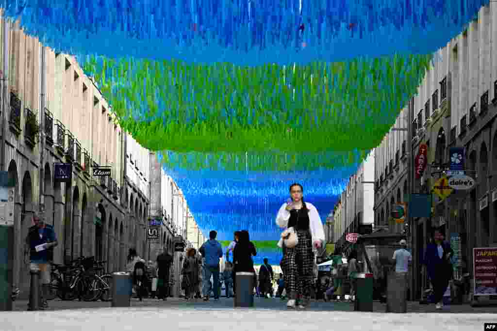 A woman walks under a shading device to fight excessive heat on a downtown shopping street in Rennes, western France, as Europe is hit by a major heatwave.