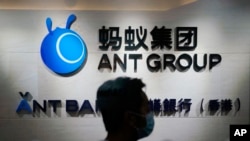 FILE - In this Oct. 23, 2020, photo, an employee walks past a logo of the Ant Group at their office in Hong Kong. 