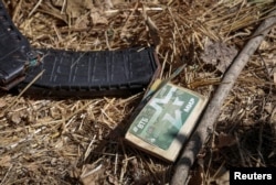 ARCHIVO - Cargadores de rifle de asalto con cartuchos y una tarjeta bancaria con la inscripción "Ejército ruso, mundo" se ven cerca del cuerpo de un soldado ruso muerto en la aldea de Blahodatne en la región de Donetsk, Ucrania, el 8 de septiembre de 2023.