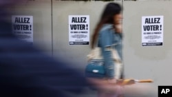 A woman walks past poster reading 'Vote' ahead of the second round of the legislative election in Strasbourg, eastern France, July 4, 2024.
